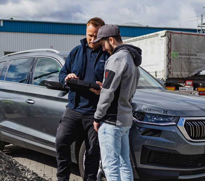 Heseding-Bewaesserungstechnik_Beregnung Zwei Mitarbeiter stehen neben einem Firmenfahrzeug von Heseding und besprechen Details auf einem Tablet. Die Szene vermittelt persönliche Beratung direkt vor Ort, schnellen Austausch und kompetenten Kundenservice – genau das, was Heseding als zuverlässigen Partner im Arbeitsalltag auszeichnet.